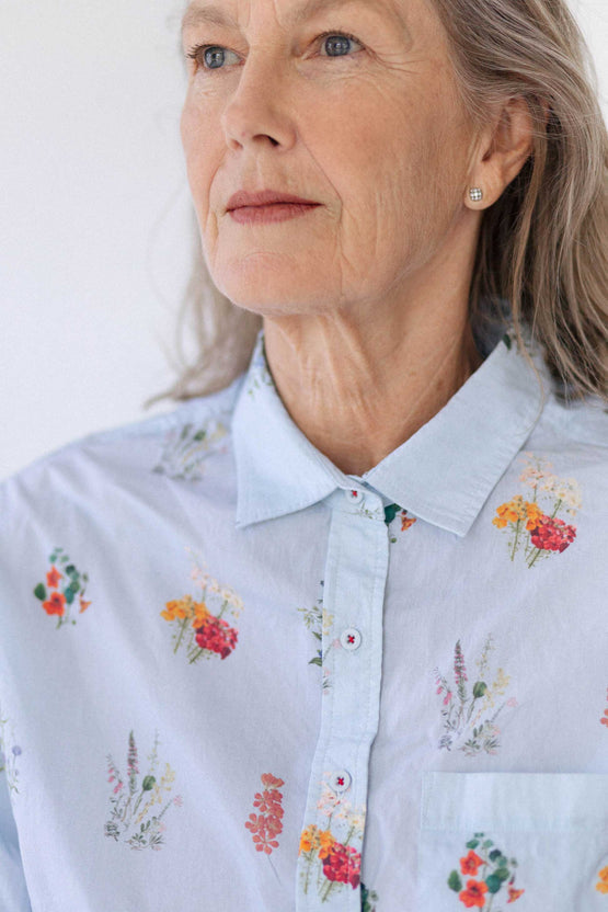 An older woman wears the Lauren Shirt in Wildflower. It is buttoned up to the collar.