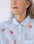 An older woman wears the Lauren Shirt in Wildflower. It is buttoned up to the collar.