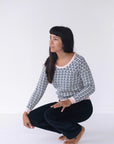 A woman crouches wearing the Tilda Jumper in Loop Pattern