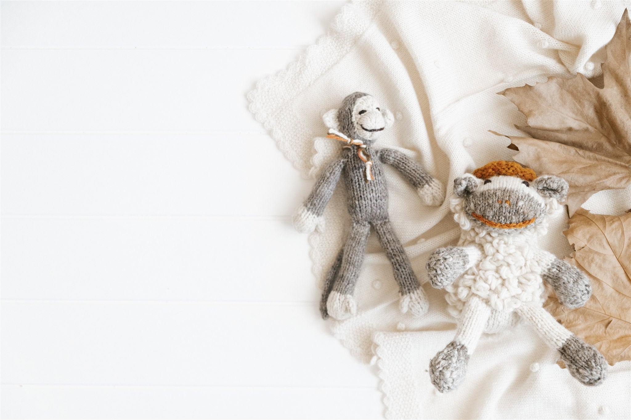 Two knitted monkey toys on a soft white fabric background